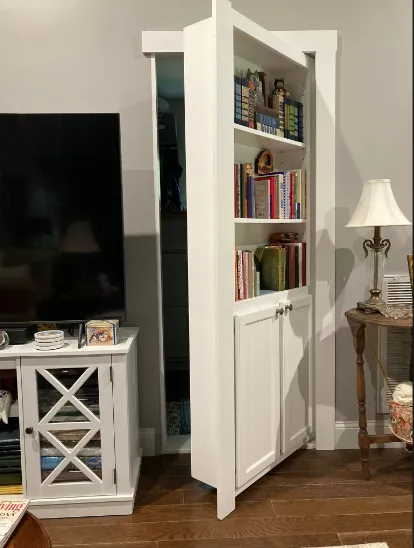 White painted bookcase door partially open in a living room setting