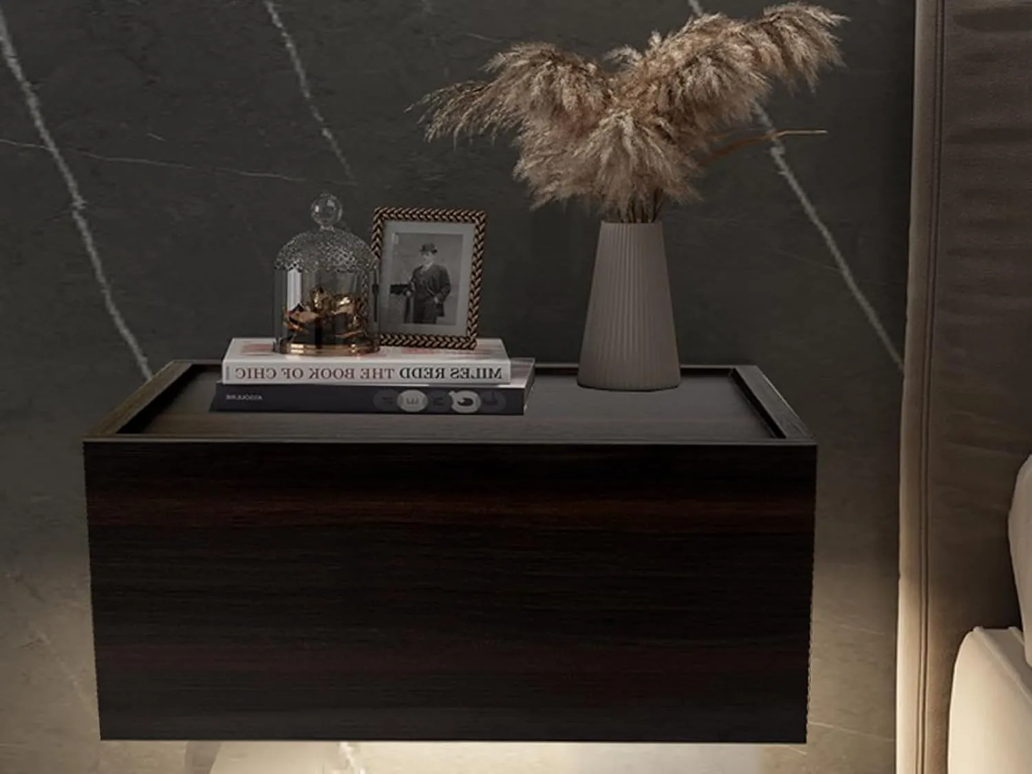 The Vigil nightstand wall-mounted beside a bed, styled with books and a vase